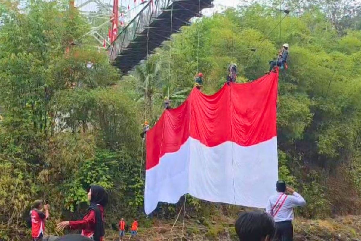Warga mengibarkan bendera Merah Putih berukuran 20x10 meter secara vertikal di Jembatan Gantung Sukamenak, Kota Tasikmalaya, Senin (17/8/2026). Shotlist.id/Foto: AB