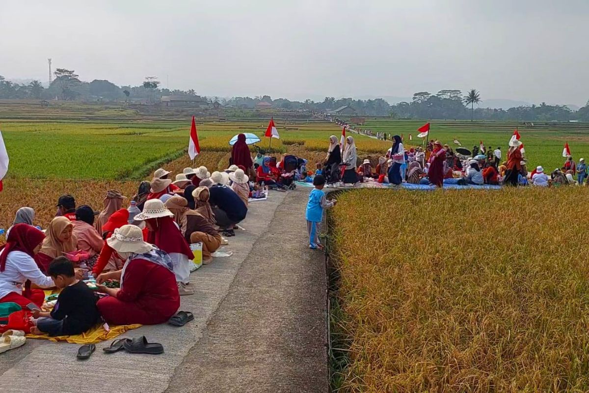 Ribuan warga Desa Cijulang, Kecamatan Cihaurbeuti, Kabupaten Ciamis, mengikuti tradisi Botram Salembur dengan makan bersama di sepanjang Jalan Usaha Tani Eretan, Rabu (19/8/2026). Shotlist.id/Foto: Agus Berrie